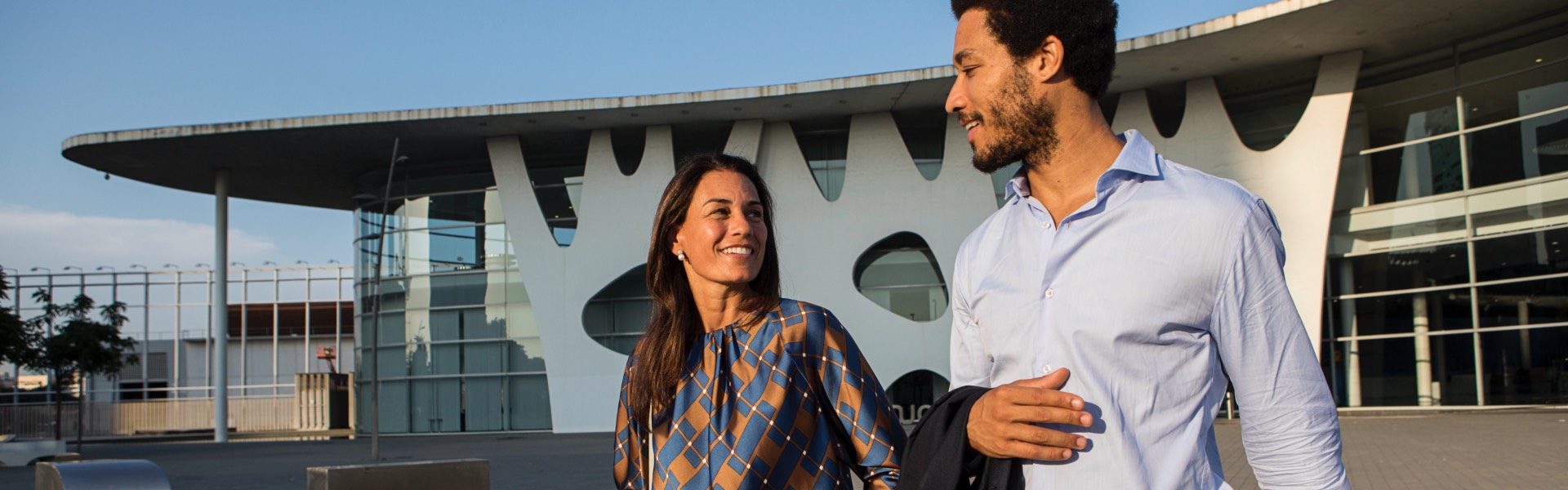 Woman and man smiling, opposite the Gran Via Fira de Barcelona Trade complex