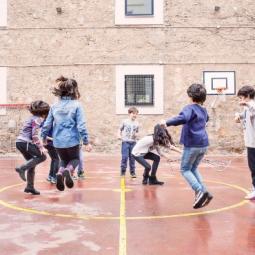 Niñas y niños saltando y jugando en el patio de la escuela