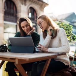 Two girls sitting at a table looking at a laptop