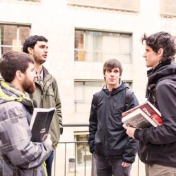 Estudiantes con carpetas a la salida de un edificio