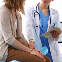 Paciente sentada en la camilla y doctora dándole la mano