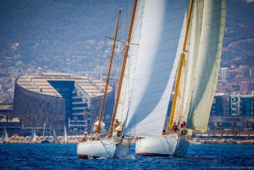 Two sailboats in the PUIG CLASSIC SAILING REGATTA. with the Barcelona coastline in the background
